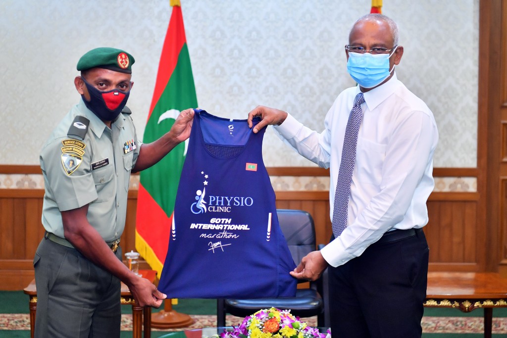 Marathoner Nasrullah Ahmed presents his 60th medal and jersey to the President
